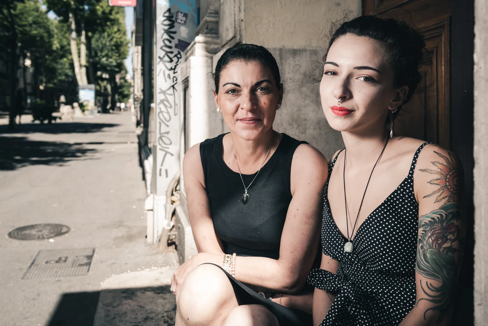 Two women seated together outside a building.