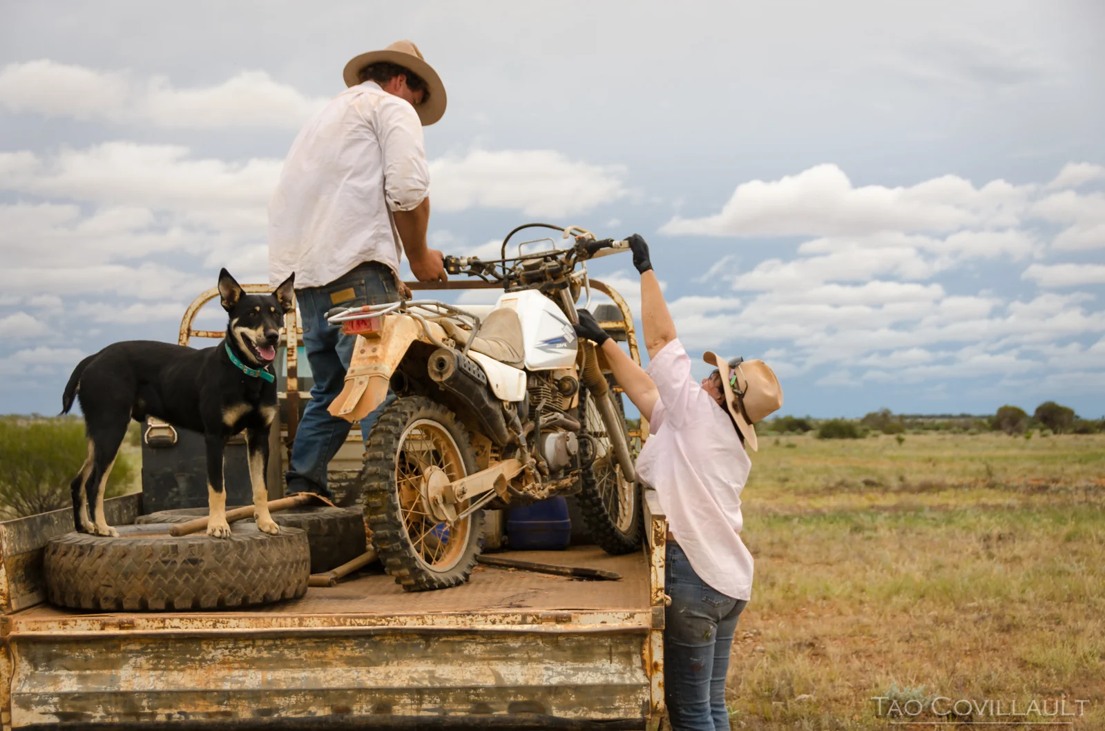 Stockmen unloading a dirt bike from a utility truck.